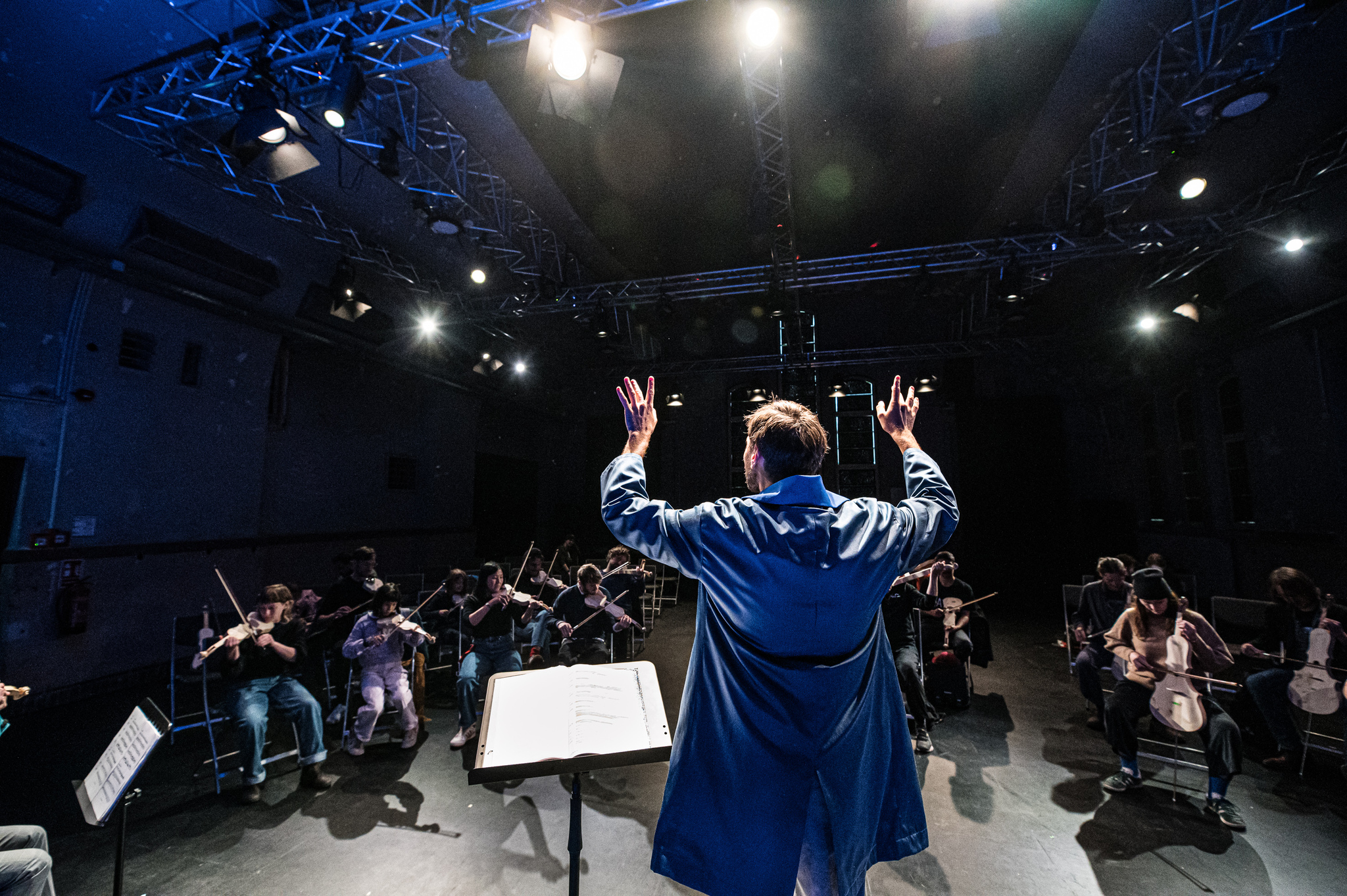 Ein Dirigent steht vor einem Orchester und dirigiert.