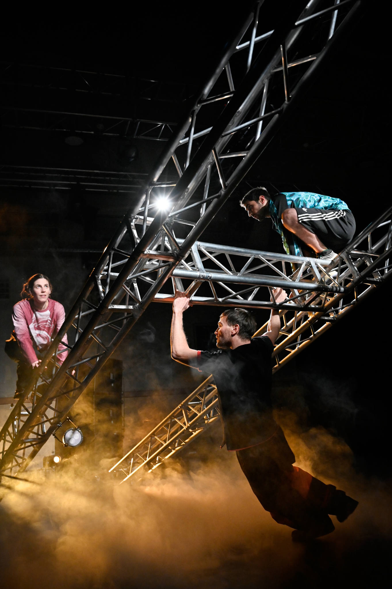 Zwei Personen klettern auf einem Gerüst, eine Person hängt dran.